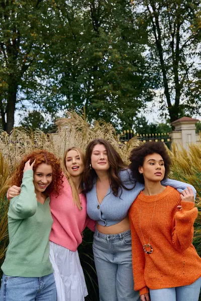Quatre femmes élégantes profitent d'une journée de printemps ensoleillée dans le parc, rayonnant de confiance et d'amitié. — Photo de stock