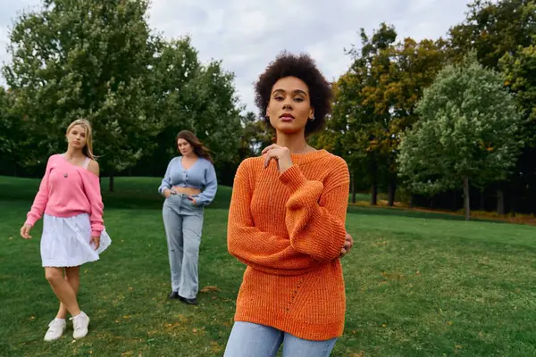 Three stylish women enjoy a beautiful spring day in a lush park, radiating confidence and elegance. — Stock Photo