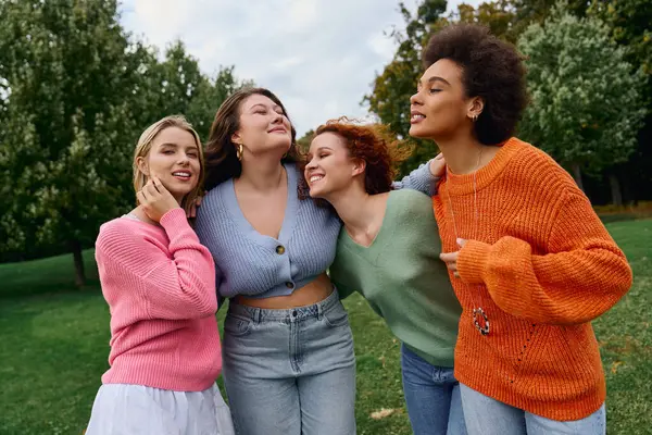 Quatre amis à la mode se côtoient dans un parc animé au printemps. — Photo de stock