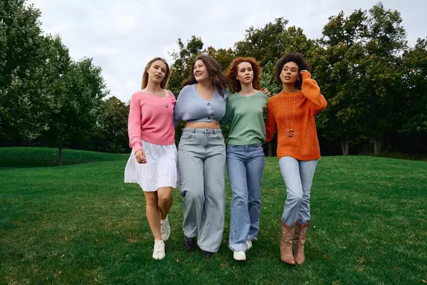 Four fashionable friends enjoy a confident walk in a beautiful park during a sunny spring day. — Stock Photo