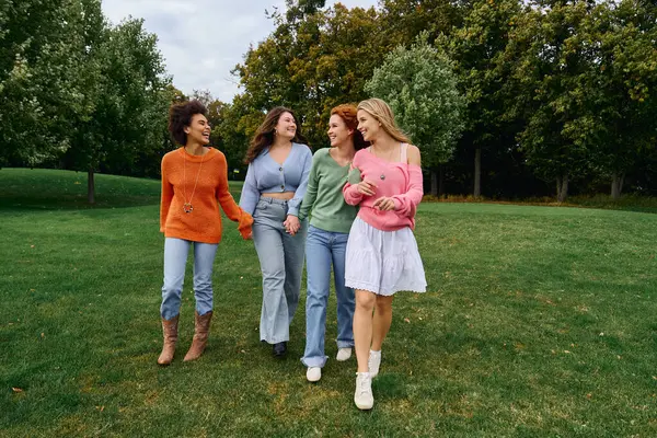 Friends embrace femininity and fashion while strolling through a lush green park in spring. — Stock Photo