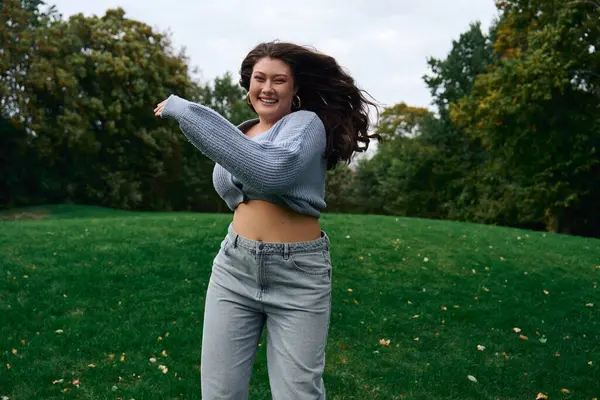 A fashionable female confidently enjoys a breezy day outdoors, twirling in a chic outfit. — Stock Photo