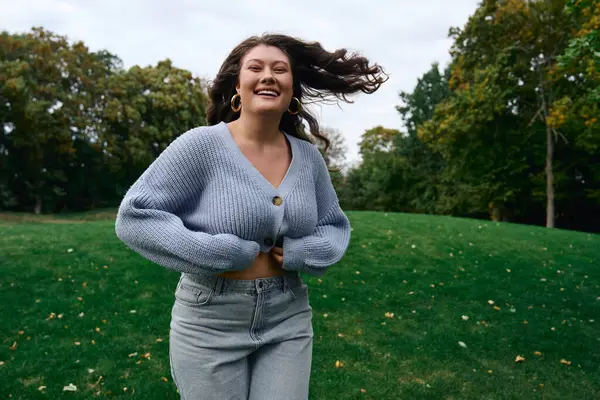 Una giovane donna elegante corre gioiosamente in un parco verde, trasudando fiducia in questa primavera.. — Foto stock