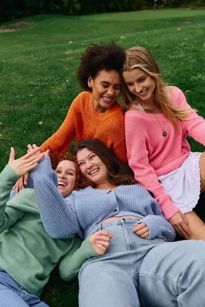 Quatre amis à la mode partagent le rire et la joie lors d'une journée de printemps ensoleillée dans le parc. — Photo de stock