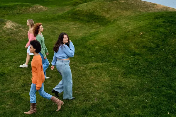 Charming women stroll gracefully through a vibrant green park, exuding confidence and style. — Stock Photo