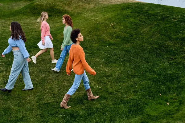 A group of four stylish women strolls confidently through a lush park, embodying spring fashion. — Stock Photo
