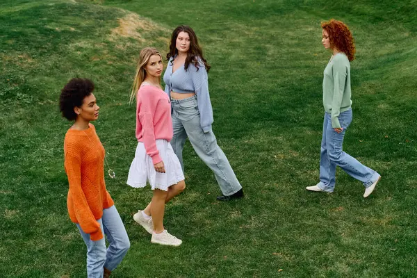 Four stylish women embrace the beauty of spring, exuding confidence in a lush green park. — Stock Photo