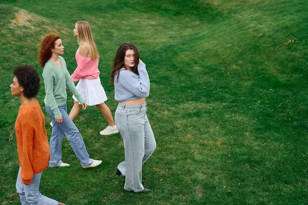 A group of fashionable friends strolls confidently through a lush green park during springtime. — Stock Photo