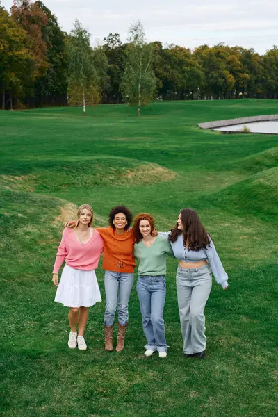 Four stylish friends stroll through a vibrant park, flaunting their fashionable outfits. — Stock Photo