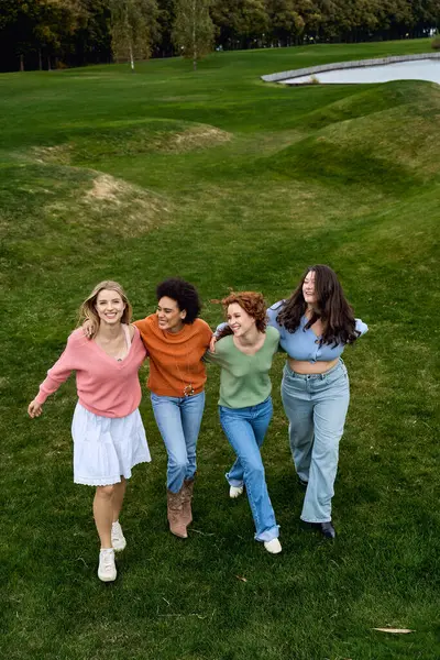Four fashionable women share joyful moments outside in a vibrant park during springtime. — Stock Photo