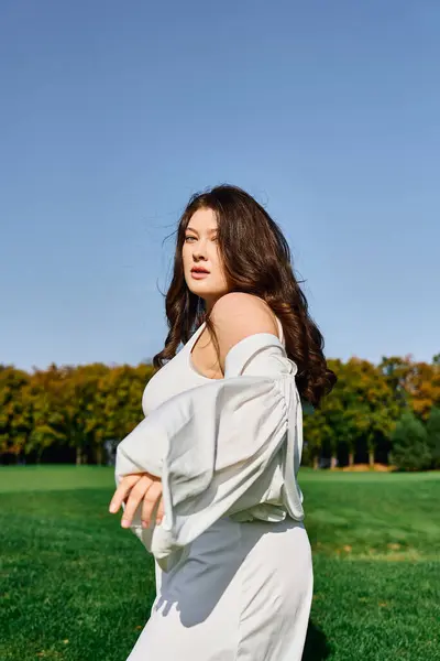 A stylish woman confidently displays her fashion in a vibrant park under a clear blue sky. — Stock Photo