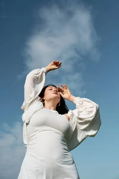 A fashionable woman embraces the outdoors while posing gracefully against a stunning sky backdrop. — Stock Photo