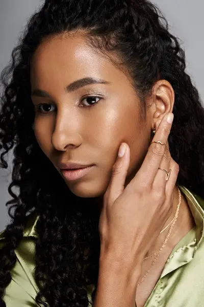 African american woman with curly hair poses gracefully in stylish attire adorned with jewellery. — Stock Photo