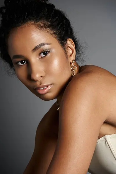 A confident african american woman displays her stylish outfit and elegant jewelry in a chic setting. — Stock Photo