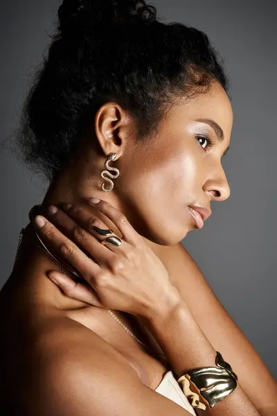 Une superbe femme afro-américaine pose gracieusement, mettant en valeur sa tenue élégante et ses bijoux. — Photo de stock