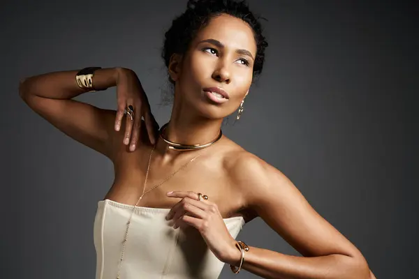 Elegante donna afroamericana mette in mostra gioielli eleganti mentre posa in un ambiente moderno. — Foto stock