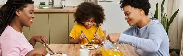 In a warm kitchen, a loving family enjoys pancakes and orange juice while bonding together. — Stock Photo
