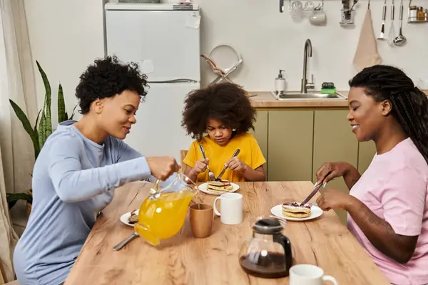 Three family members share a joyful breakfast of pancakes, laughter, and love. — Stock Photo