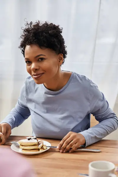 Una donna gioiosa che fa colazione con deliziosi pancake. — Foto stock