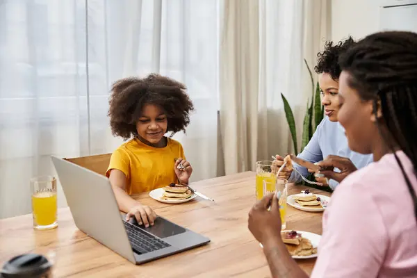 Una familia lgbt comparte risas y panqueques mientras se conectan durante el desayuno en una habitación cálida y acogedora. - foto de stock