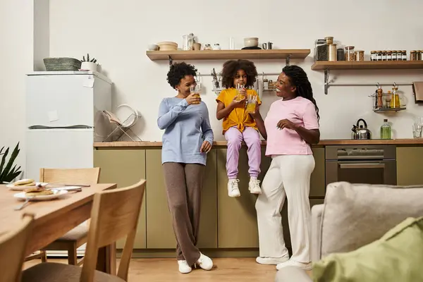 Three joyful family members enjoy drinks while bonding at home, radiating love and happiness. — Stock Photo