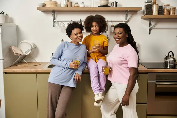 A loving lgbt family shares laughter and joy in a cozy kitchen while enjoying a refreshing beverage. — Stock Photo