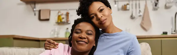 Two loving women share a warm embrace in a cozy kitchen, radiating happiness. — Stock Photo