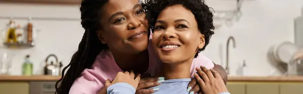 Two loving women embrace each other, sharing a joyful moment of togetherness in the kitchen. — Stock Photo
