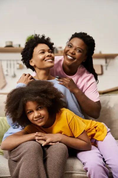 Three family members share a warm moment, laughing and embracing in their cozy living room. — Stock Photo