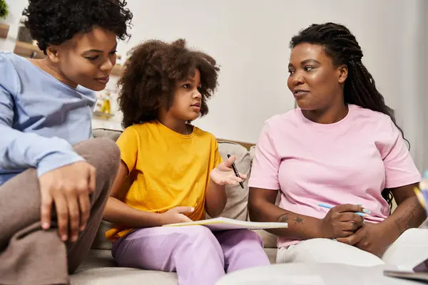 A joyful lgbt family engages in meaningful conversation with their daughter while drawing together. — Stock Photo