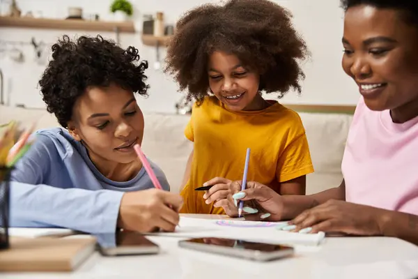 Daughter watches as two parents engage in artistic activities at their welcoming living room table. — Stock Photo