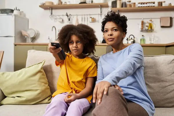 A mother and daughter share a warm moment on the couch, enjoying a TV show together. — Stock Photo