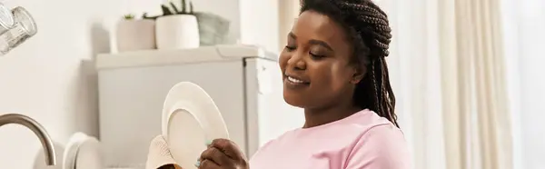 Uma jovem mulher lavando pratos e sorrindo feliz em casa. — Fotografia de Stock