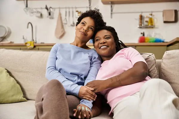 Dos mujeres cariñosas se abrazan, compartiendo sonrisas y calidez en su hogar. - foto de stock