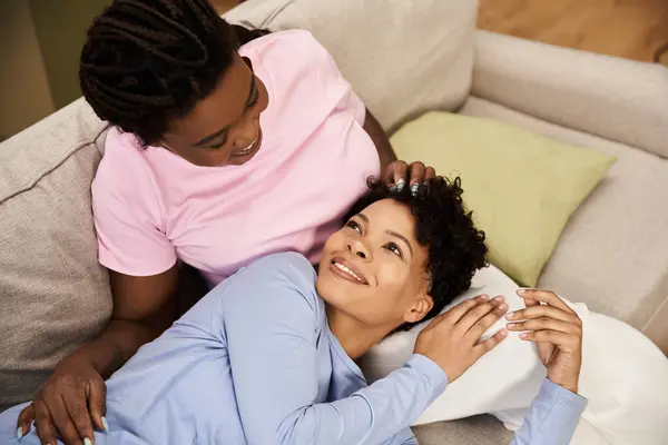 Eine junge Familie teilt einen zärtlichen Moment auf einem Sofa, genießt die Gesellschaft und das Lachen des anderen. — Stockfoto