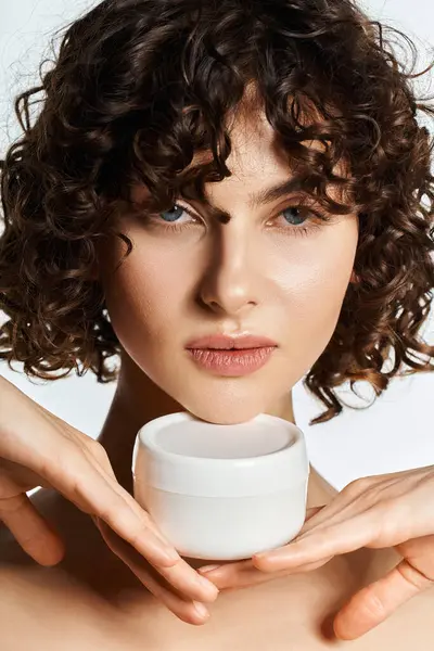 A captivating young woman shows off a skincare product in her beautifully curled hands. — Stock Photo