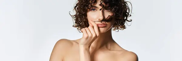 Giovane donna posa giocosamente, ostentando i capelli ricci e la bellezza naturale in luce intensa. — Foto stock