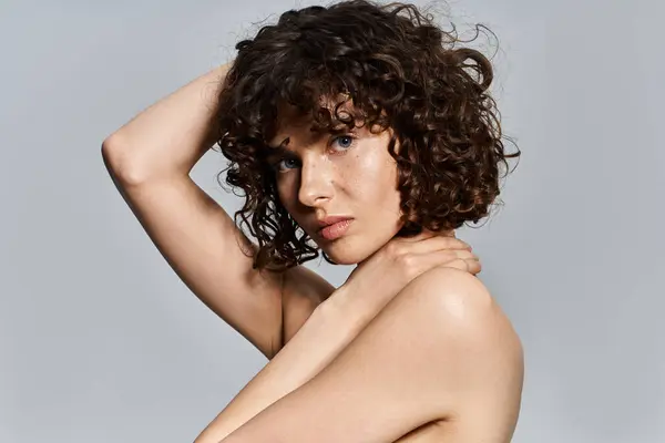 Young woman with curly hair poses artistically, radiating confidence and grace. — Stock Photo