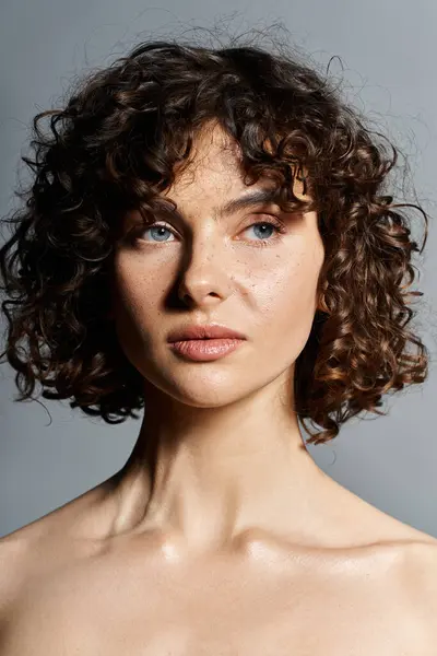 A young woman with curly hair and blue eyes showcases her natural beauty in soft lighting. — Stock Photo