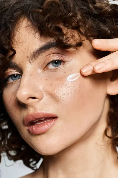 A young woman boosts her natural beauty with cream, radiating confidence. — Stock Photo