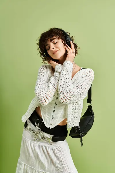 A lovely young woman with curly hair listens to music, radiating joy in a vibrant indoor space. — Stock Photo