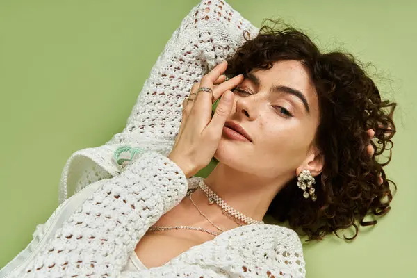 Young woman with curly hair poses gracefully, showcasing her beauty and stylish accessories. — Stock Photo
