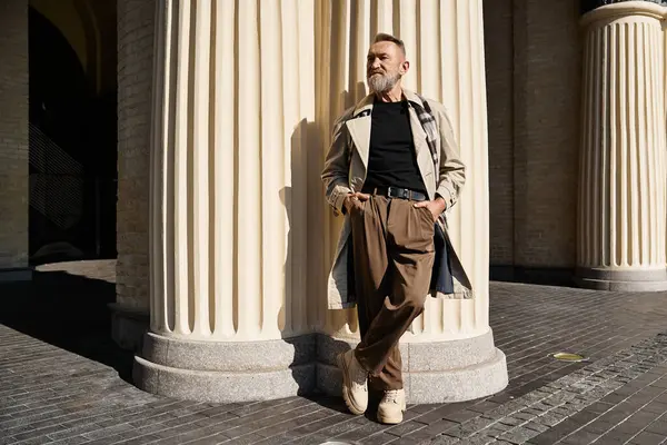 A dapper senior man confidently leans against a column in a cityscape. — Stock Photo