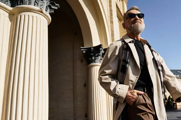 A fashionable senior man walks with confidence through an urban area, dressed in chic attire. — Stock Photo