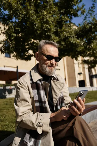 A dapper senior man dressed in fashionable attire sits comfortably outdoors under a bright blue sky. — Stock Photo