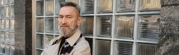 Ein gutaussehender älterer Mann geht durch eine urbane Umgebung, elegant gekleidet in modischer Kleidung. — Stock Photo