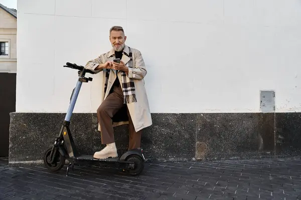 Ein stilvoller Senior in schicker Kleidung steht lässig auf einem Motorroller im Herzen der Stadt. — Stockfoto