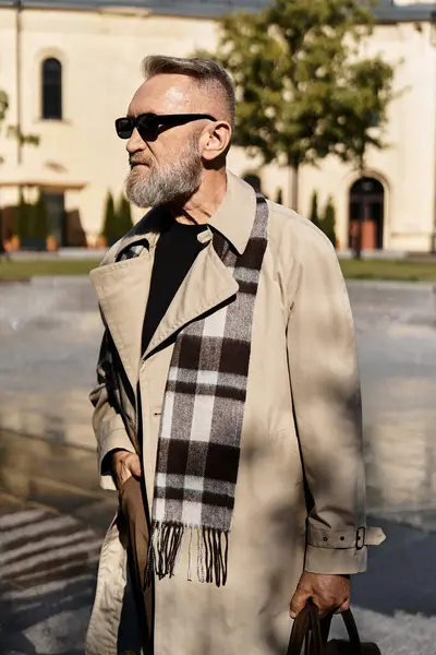 A stylish senior man enjoys a leisurely walk through a vibrant city park, in chic attire. — Stock Photo