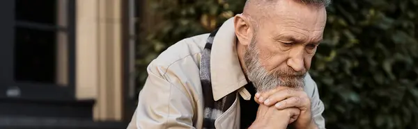 Шикарний старший чоловік в модному вбранні відображає задумливо на фоні яскравого міста. — стокове фото