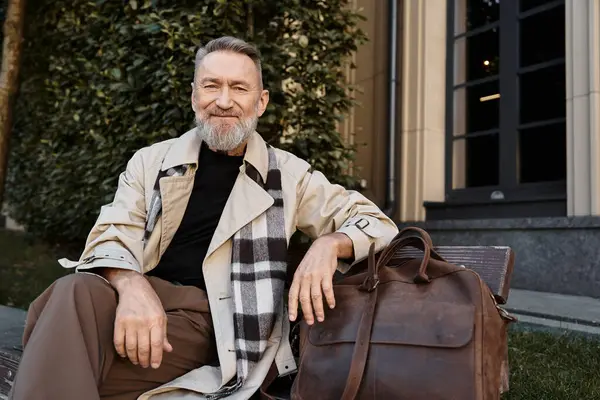 A debonair senior man sits on a bench, exuding confidence in his chic attire. — Stock Photo